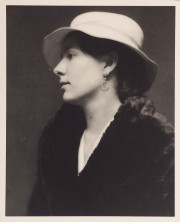 Portrait of woman in profile, with earring, white hat & black coat