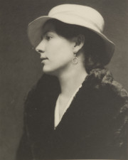 Portrait of woman in profile, with earring, white hat, black coat