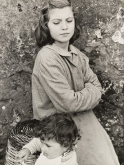 Young woman with arms folded looking at child