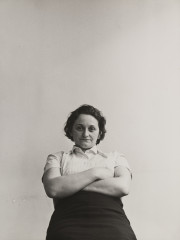 Woman with arms folded looking down at camera