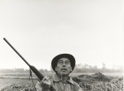 Hunter with shotgun, whistle in mouth, looking up at target