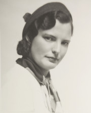Portrait of a woman in hat, patterned scarf around neck, white coat
