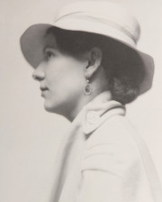 Portrait of woman in profile, with earring, white hat, white coat