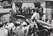 Group on balcony overlooking crowd of people, horse with feathers