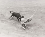 Bullfighter and bull in ring, bull attacking cape