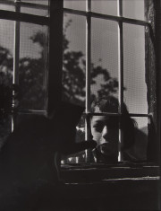 Child looking through screened window