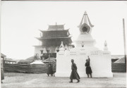 Three men walking around white shrine, Mongolia