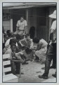 After giving a concert in a cotton field in Greenwood, Mississippi, Bob Dylan plays behind the SNCC office. Bernice Reagon, one of the original Freedom Singers and today leader of Sweet Honey in the Rock, listens. Mendy Sampstein sits behind Dylan