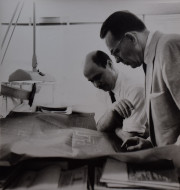 Men in ties looking at building blueprints